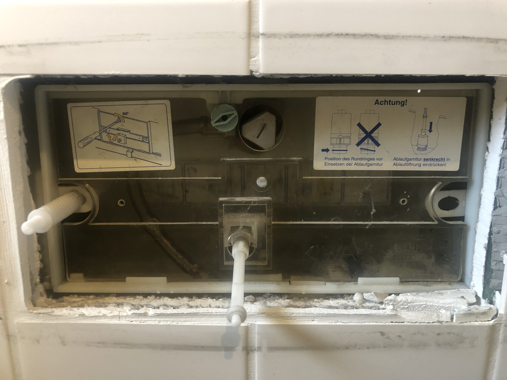 Back of a built-in dishwasher with hoses and installation instructions.
