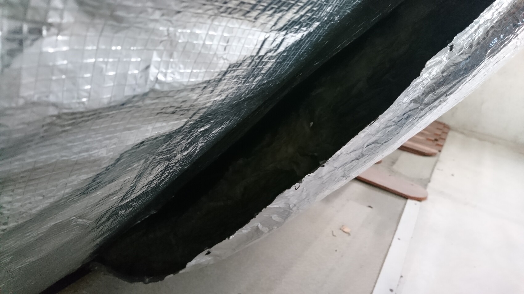 Close-up of aluminum insulation foil with gap and dark cavity behind.