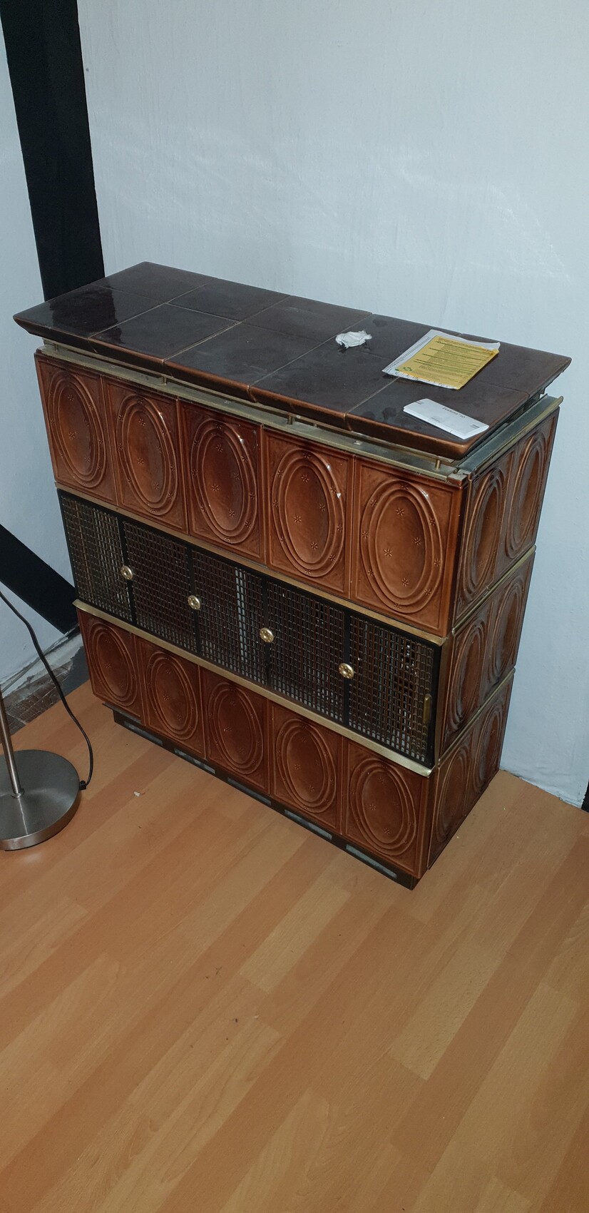 Vintage brown ceramic cabinet with circular patterns, lattice fronts, on wooden floor.