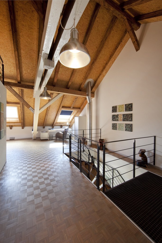 Open attic space with wooden beams, roof structure, staircase and railing