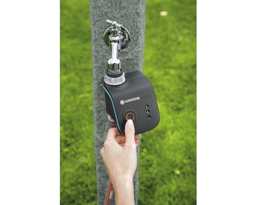 Hand operated Gardena irrigation timer on a water tap mounted on a post, hose connected.
