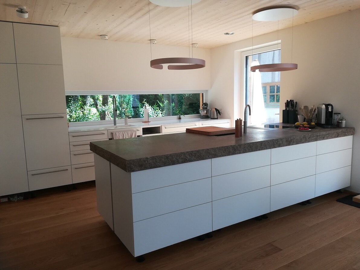 Modern kitchen with white island, stone countertop, and wooden floor.