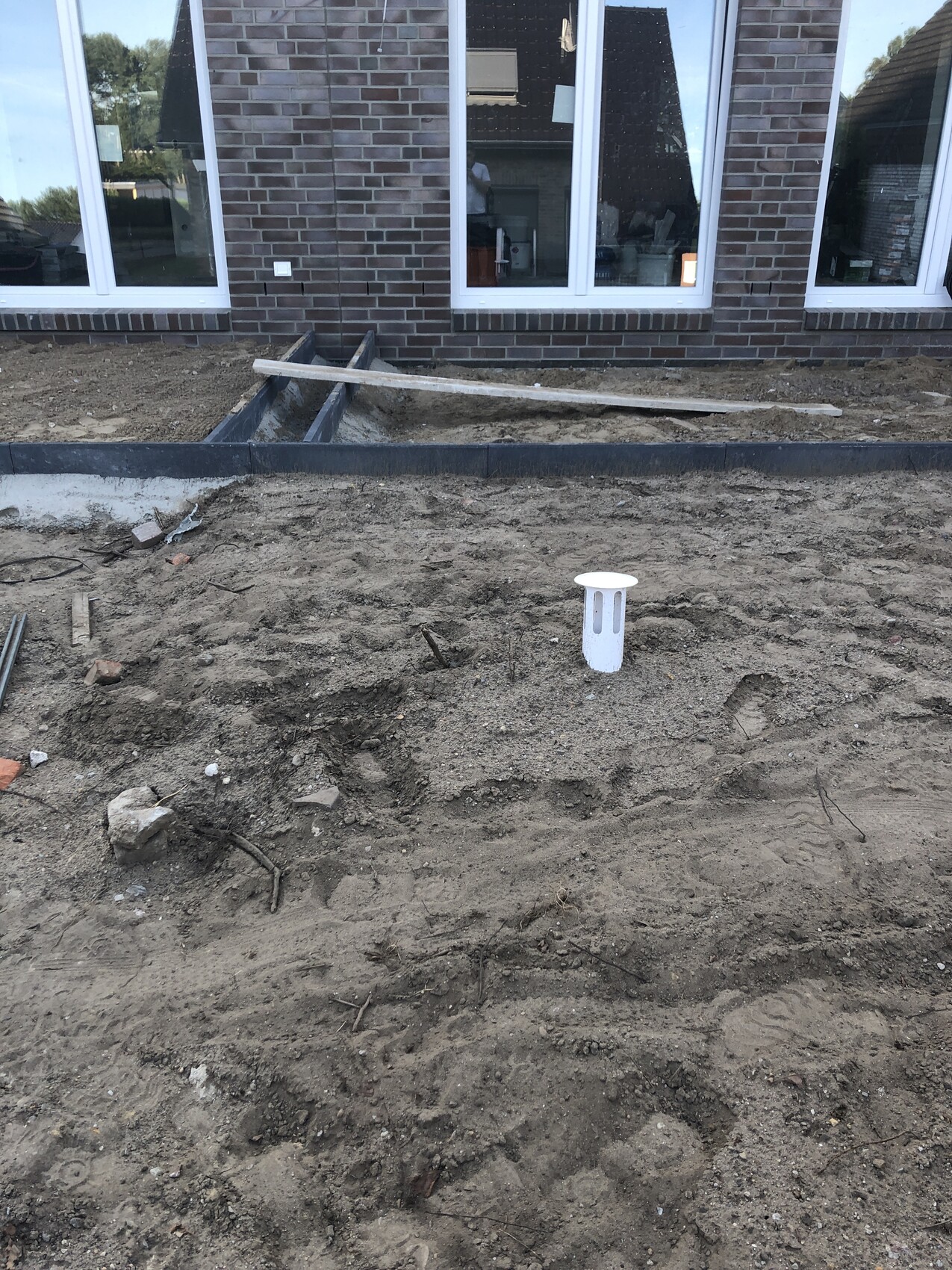 Baugrundarbeiten vor Wohnhaus mit Fundamentrinnen, Erdaushub und Abwasserschacht