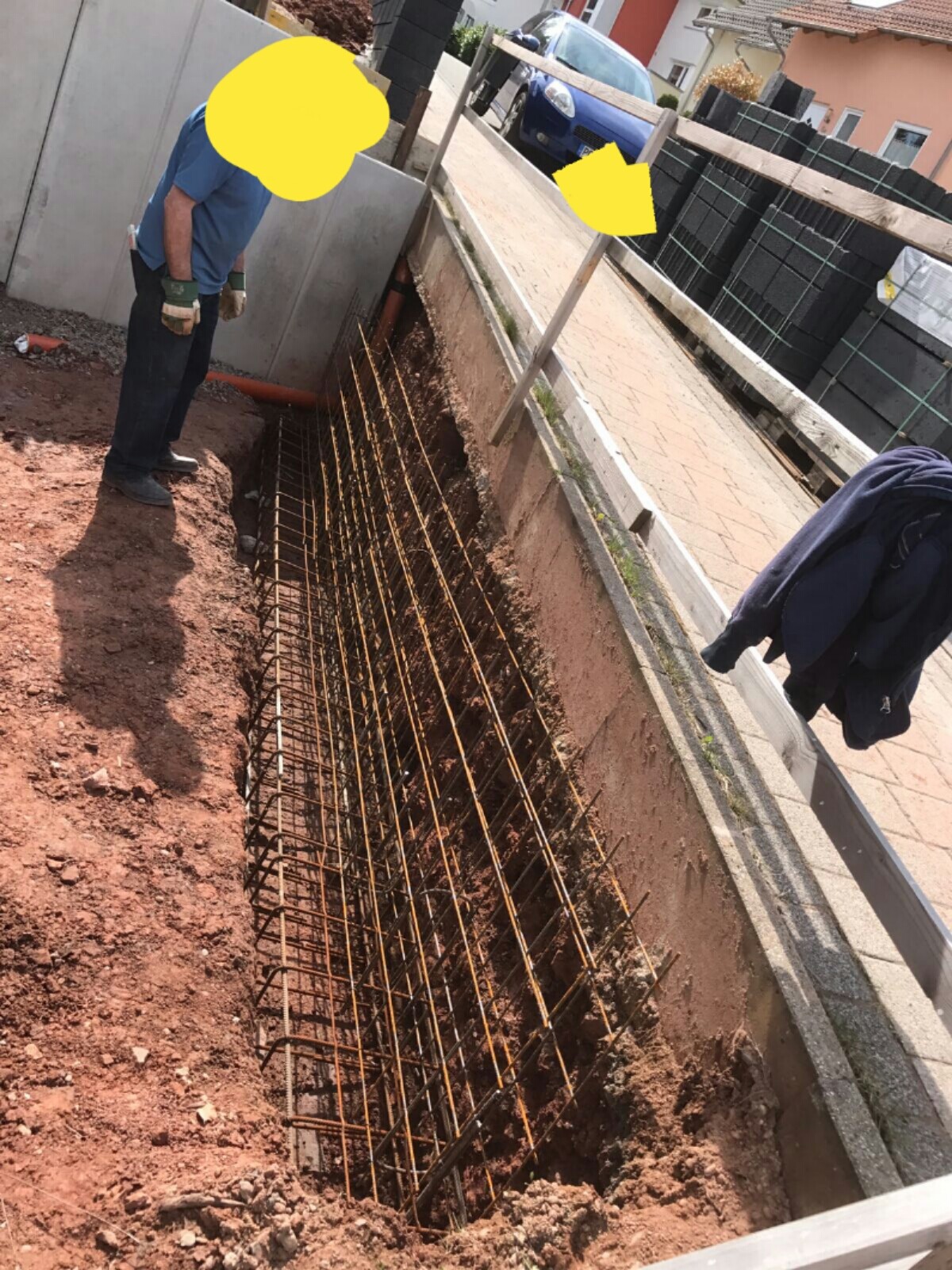 Construction worker next to excavation pit with steel reinforcement in the foundation area