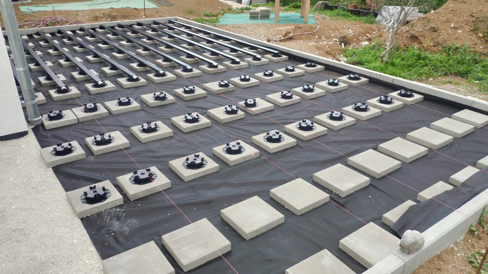 Many concrete slabs with black round holders on foil, visible red marking strings.
