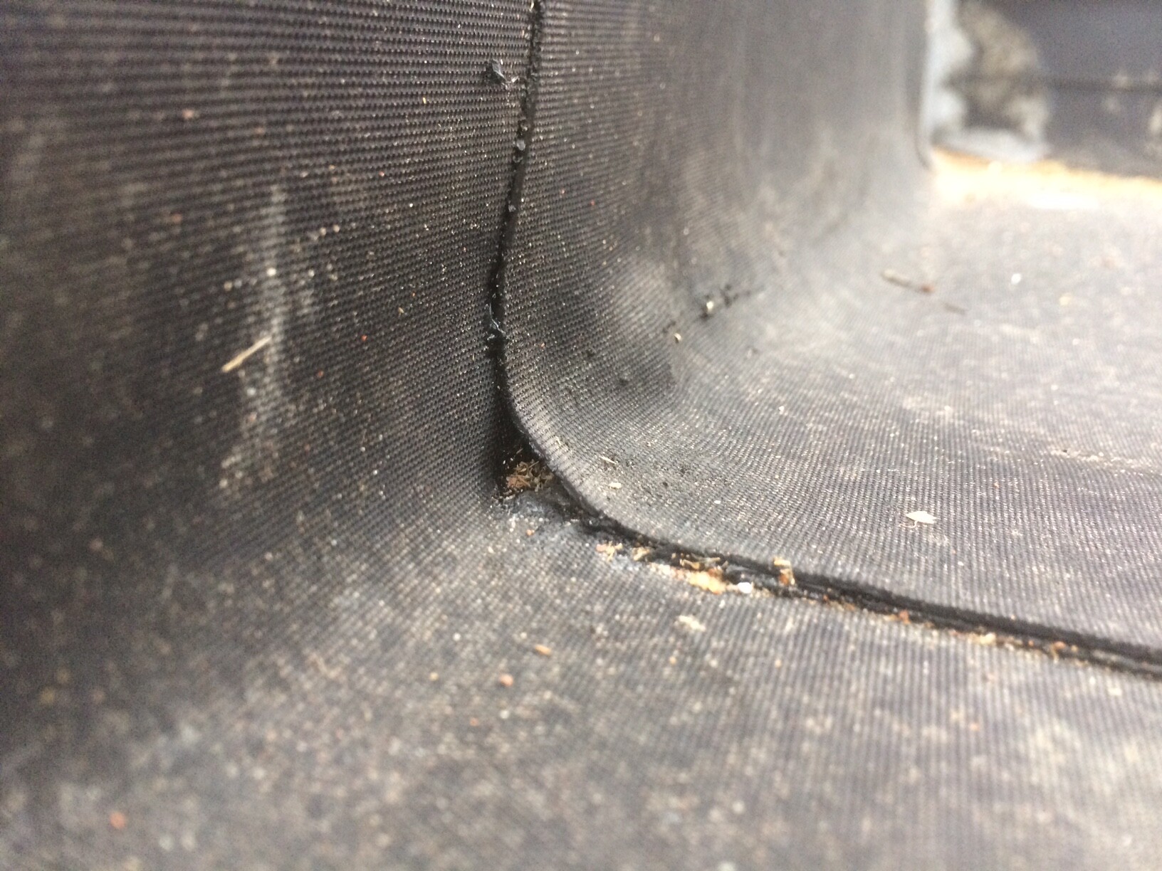 Close-up of a black membrane with a seam and dust particles.