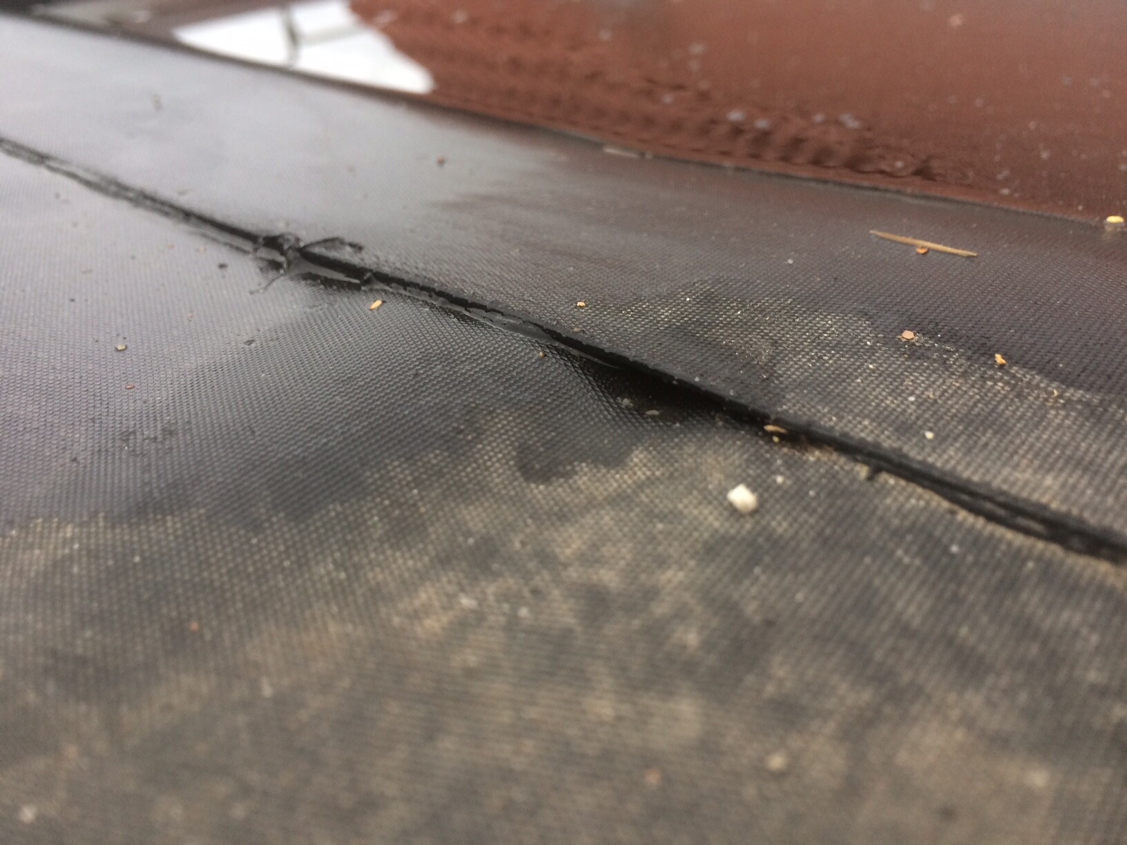 Close-up of black membrane with seam, dust and small particles.