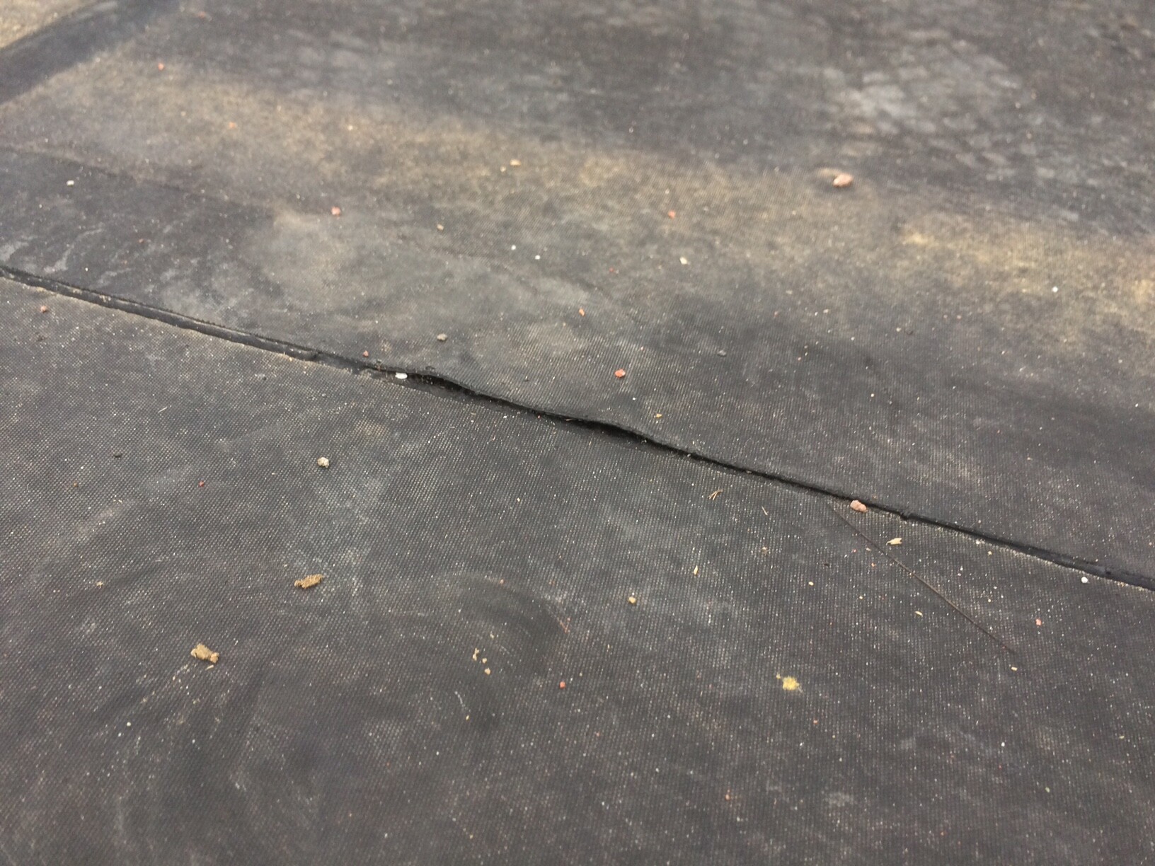 Close-up of dark fabric floor with seam and dust particles.