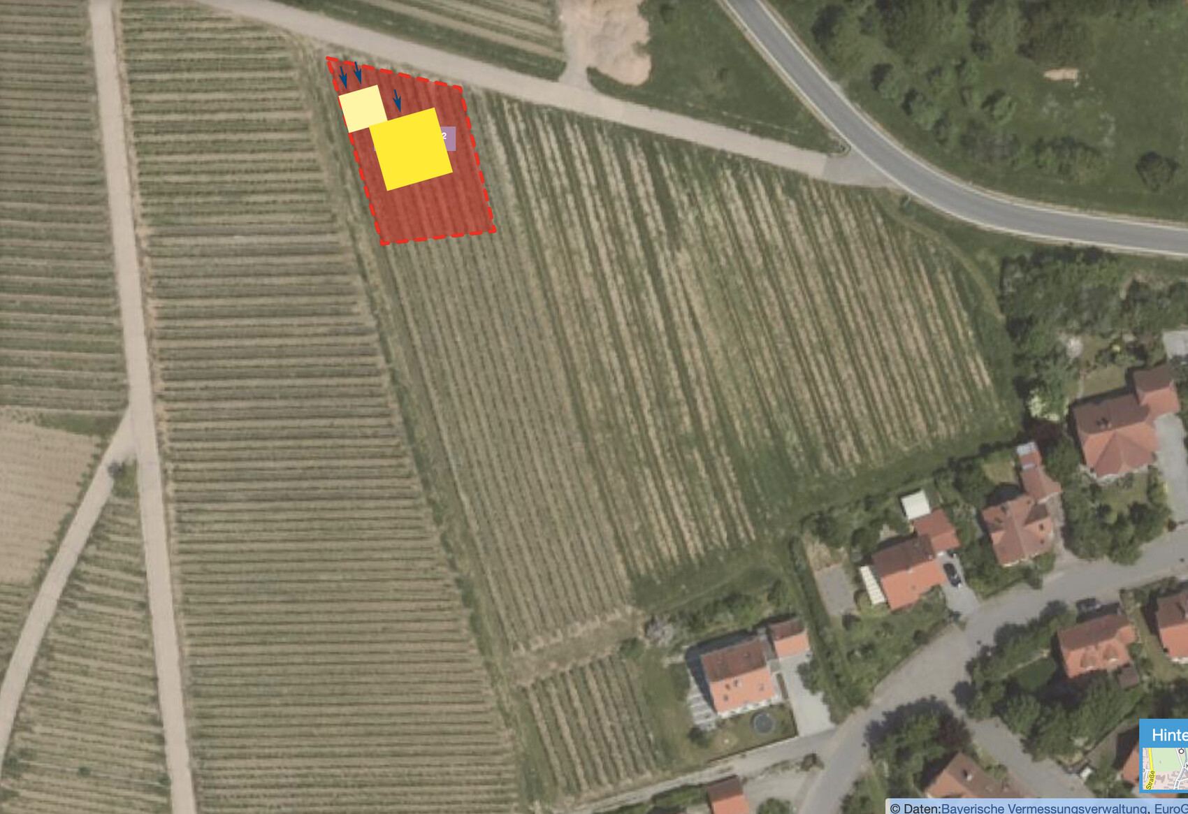 Aerial view of a marked building plot in a rural area next to residential houses.