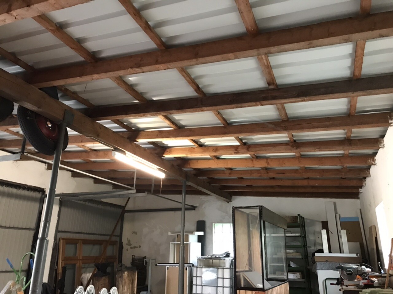 Workshop/storage room with exposed wooden beam ceilings, shelves, and tools.