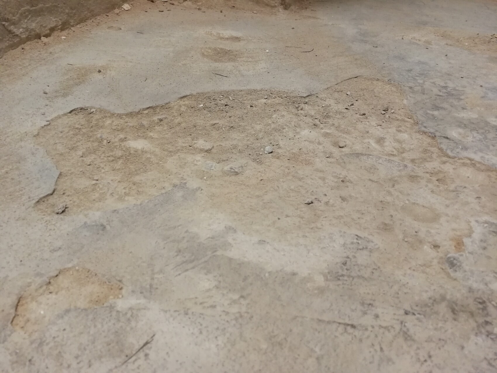 Concrete floor with irregular dust and dirt spots.