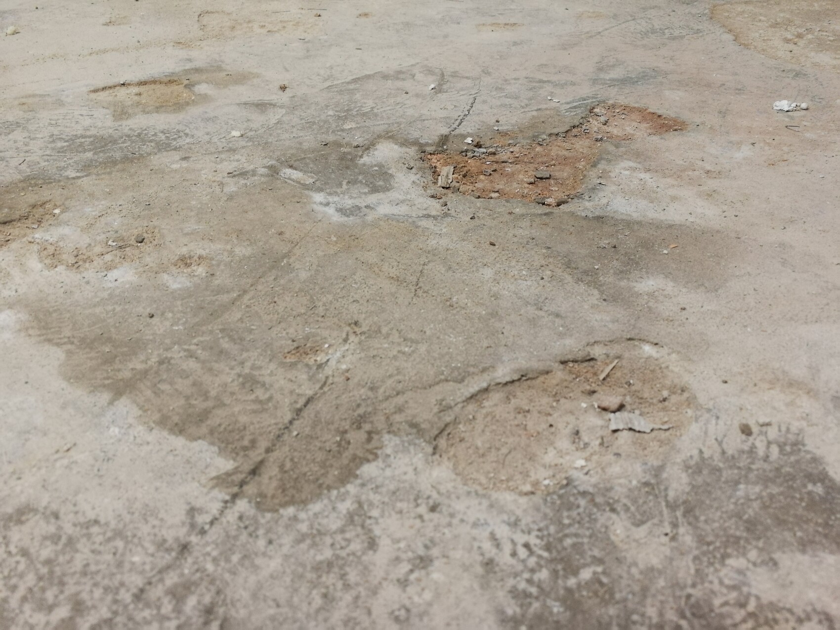 Cracked concrete floor with stains and loose debris.