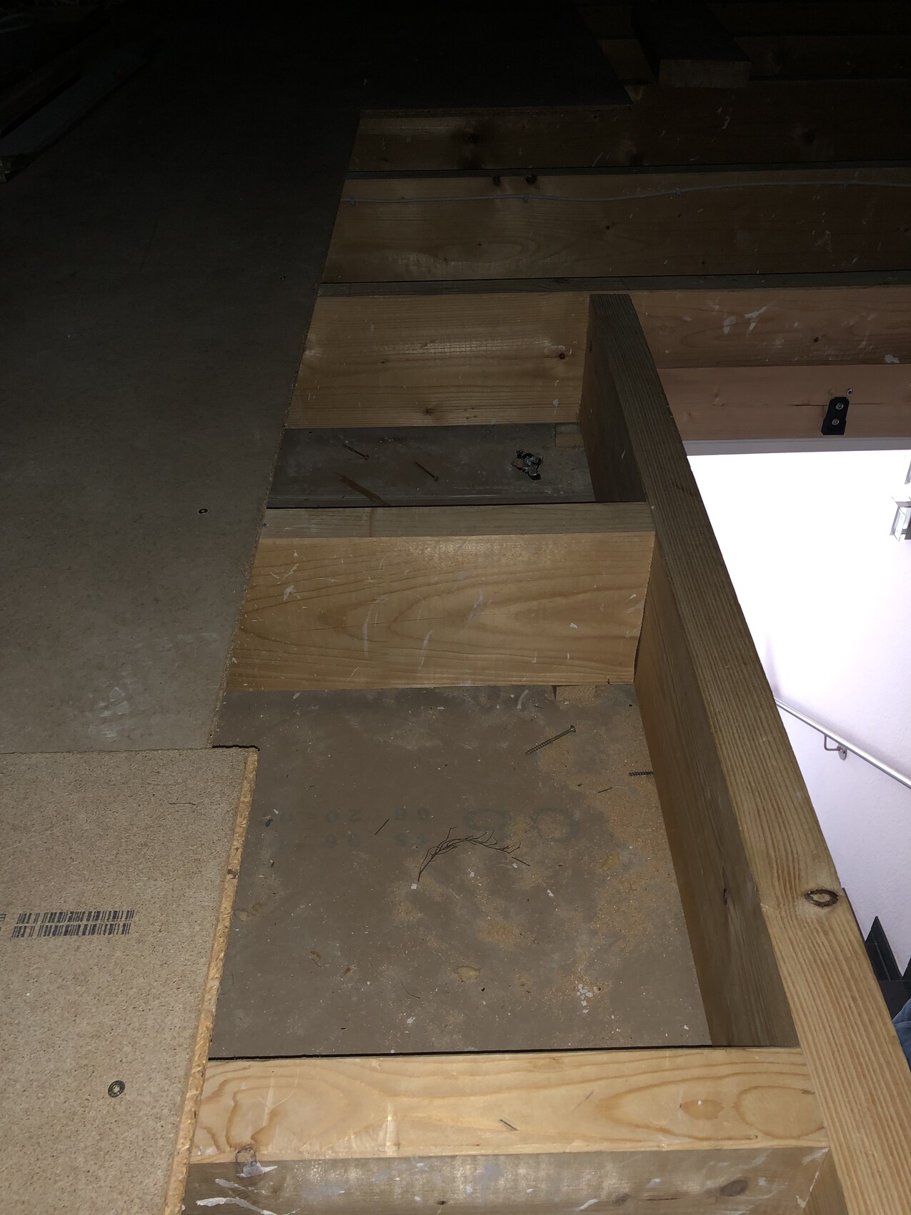 Offene Bodenöffnung in einer Holzkonstruktion mit Brettern, Staub und Nägeln.