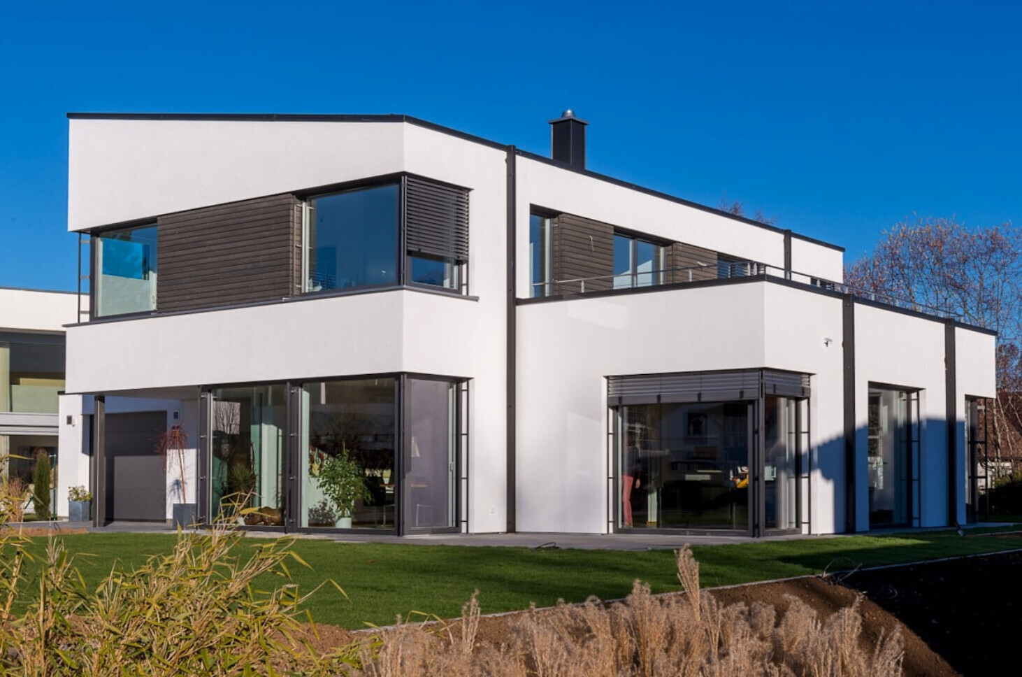 Modern white architect-designed house with large glass facades, balconies, and garden area