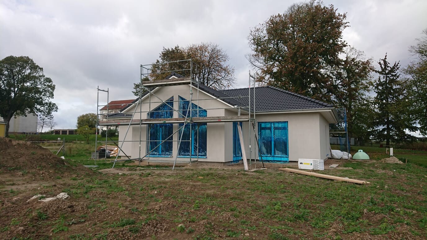 Single-family house under construction with scaffolding and blue protective film on windows