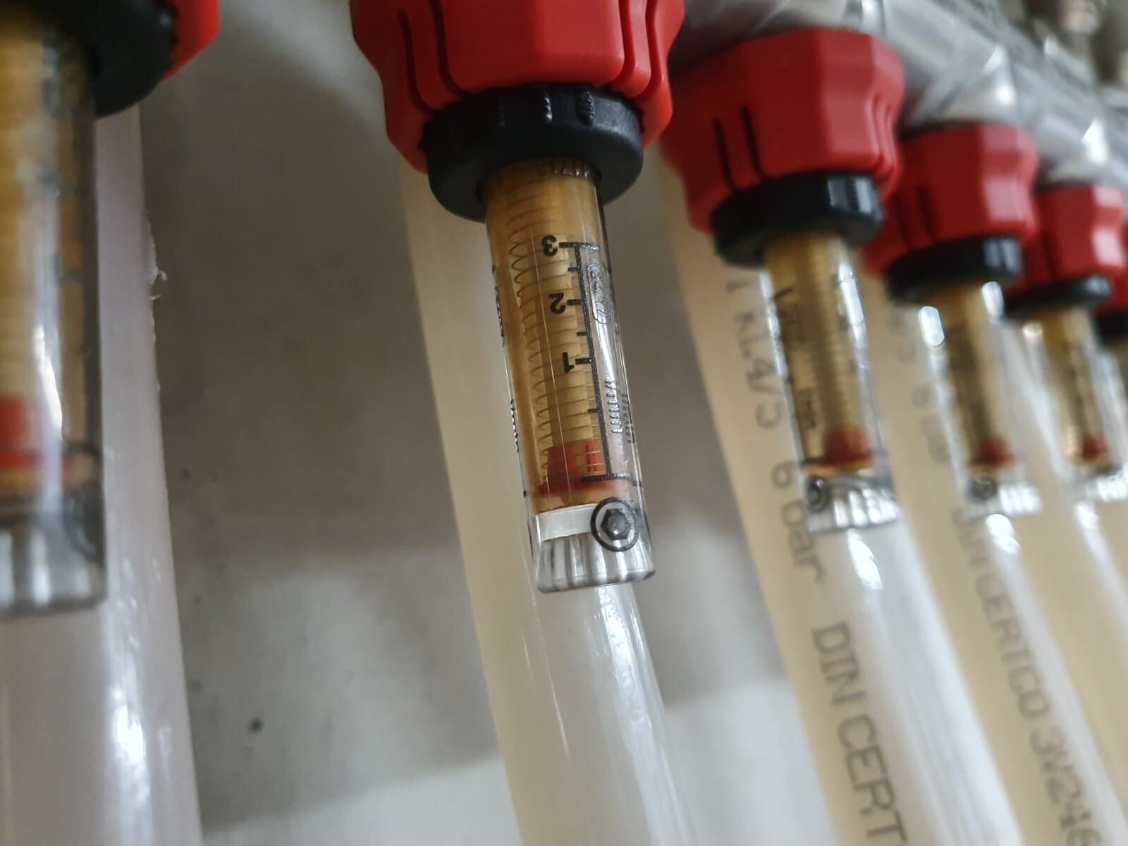 Close-up of piping with flow scale and red connections in building services installation