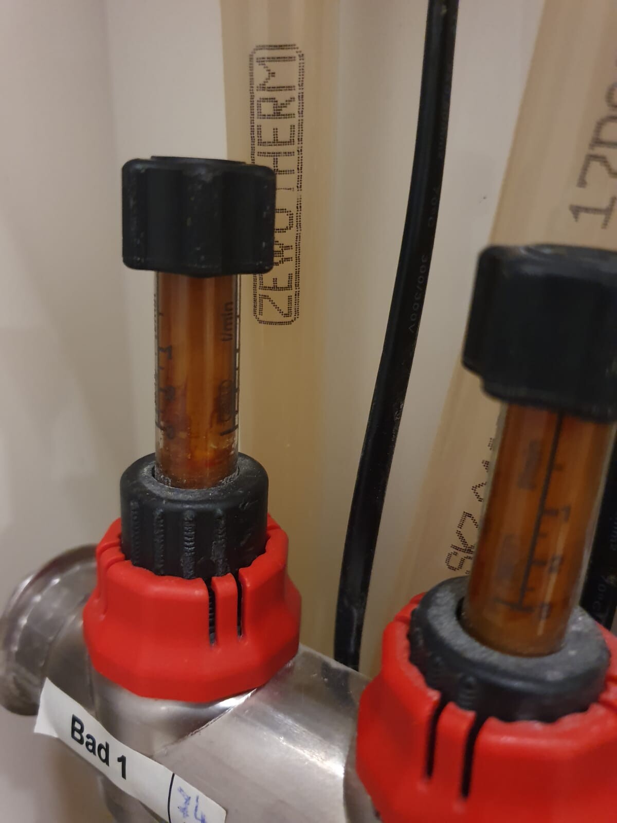 Close-up of sanitary pipes with red shut-off valves in the bathroom.
