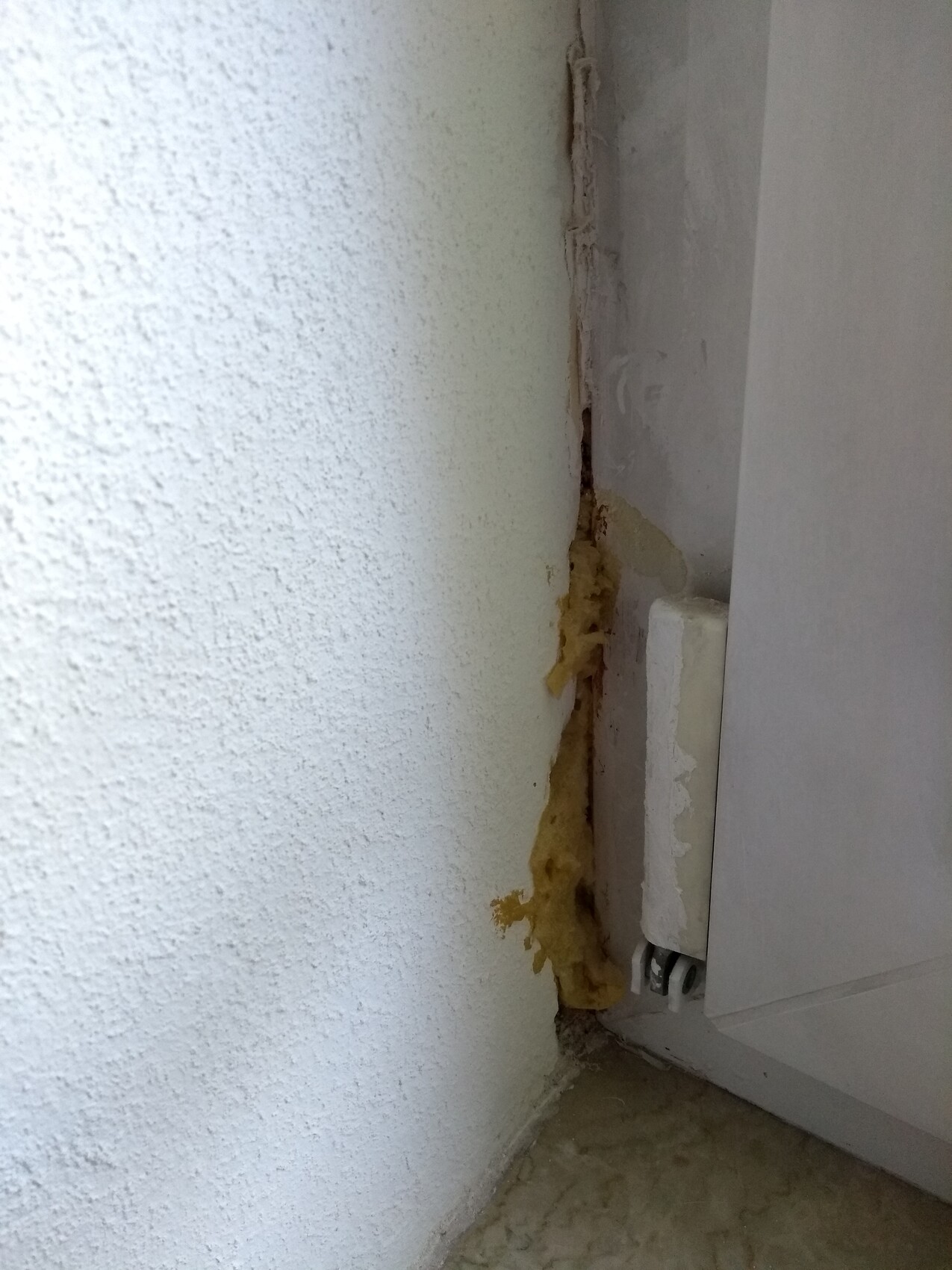Spalt zwischen Wand und Türrahmen mit gelbem Dämmstoffschaum sichtbar