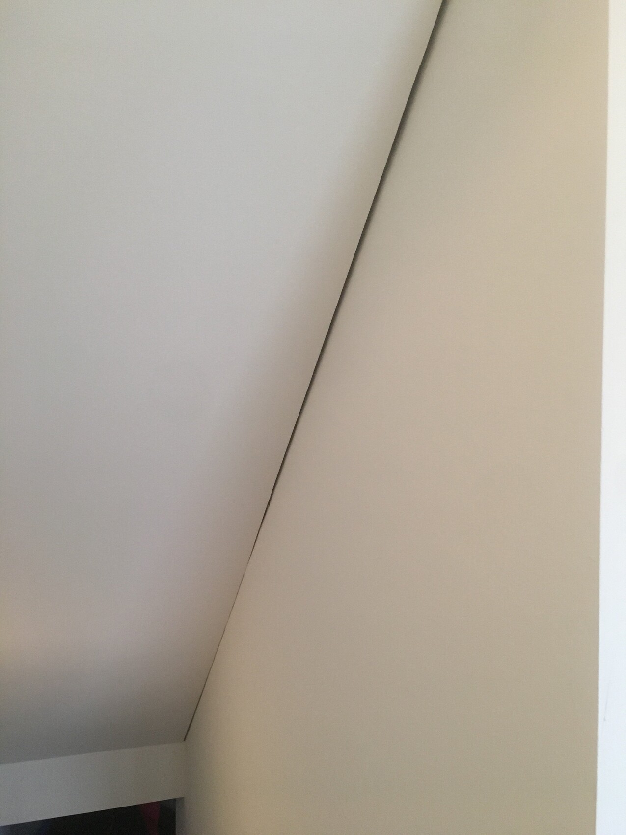 Close-up of an interior corner: sloped ceiling meets wall with a diagonal edge.