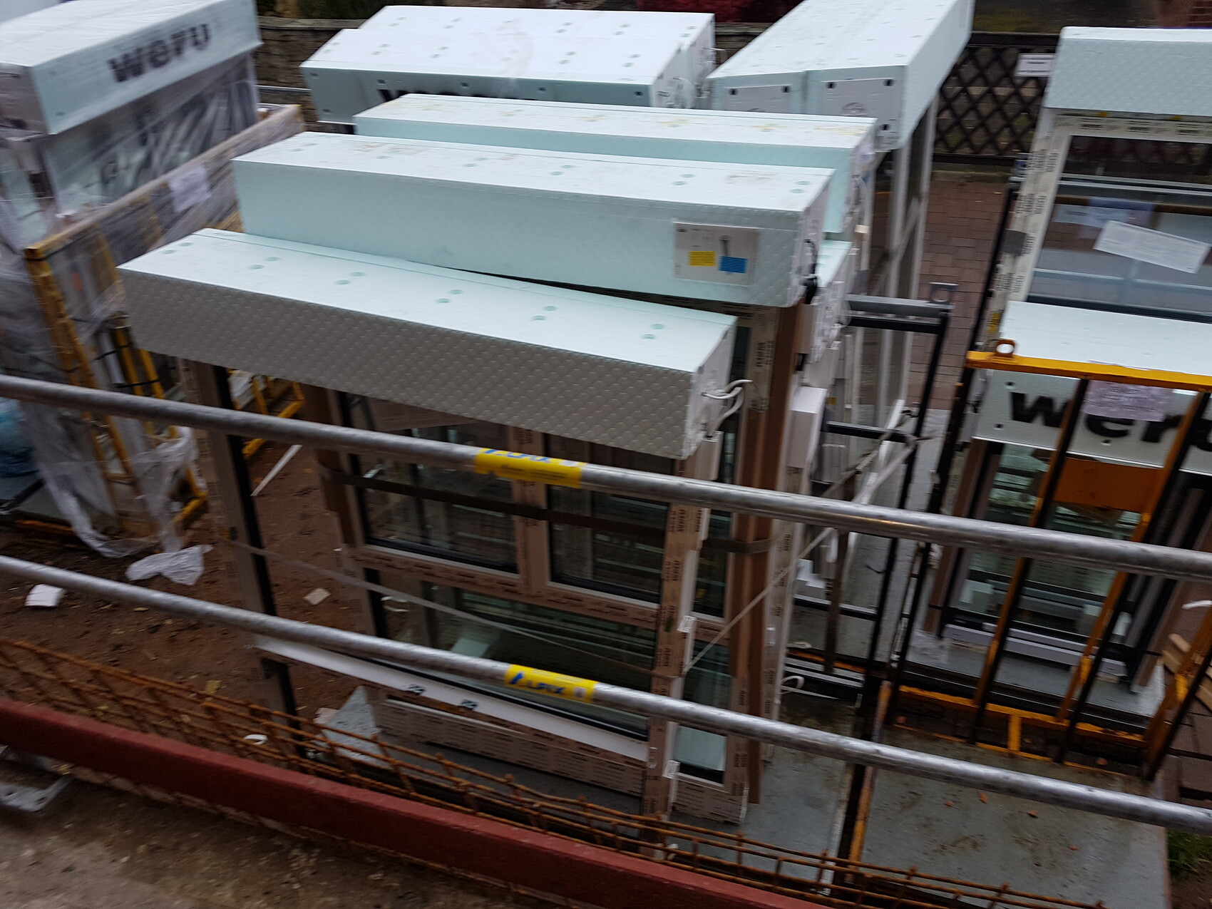 Construction site with window frames and insulation panels on scaffolding during window installation.