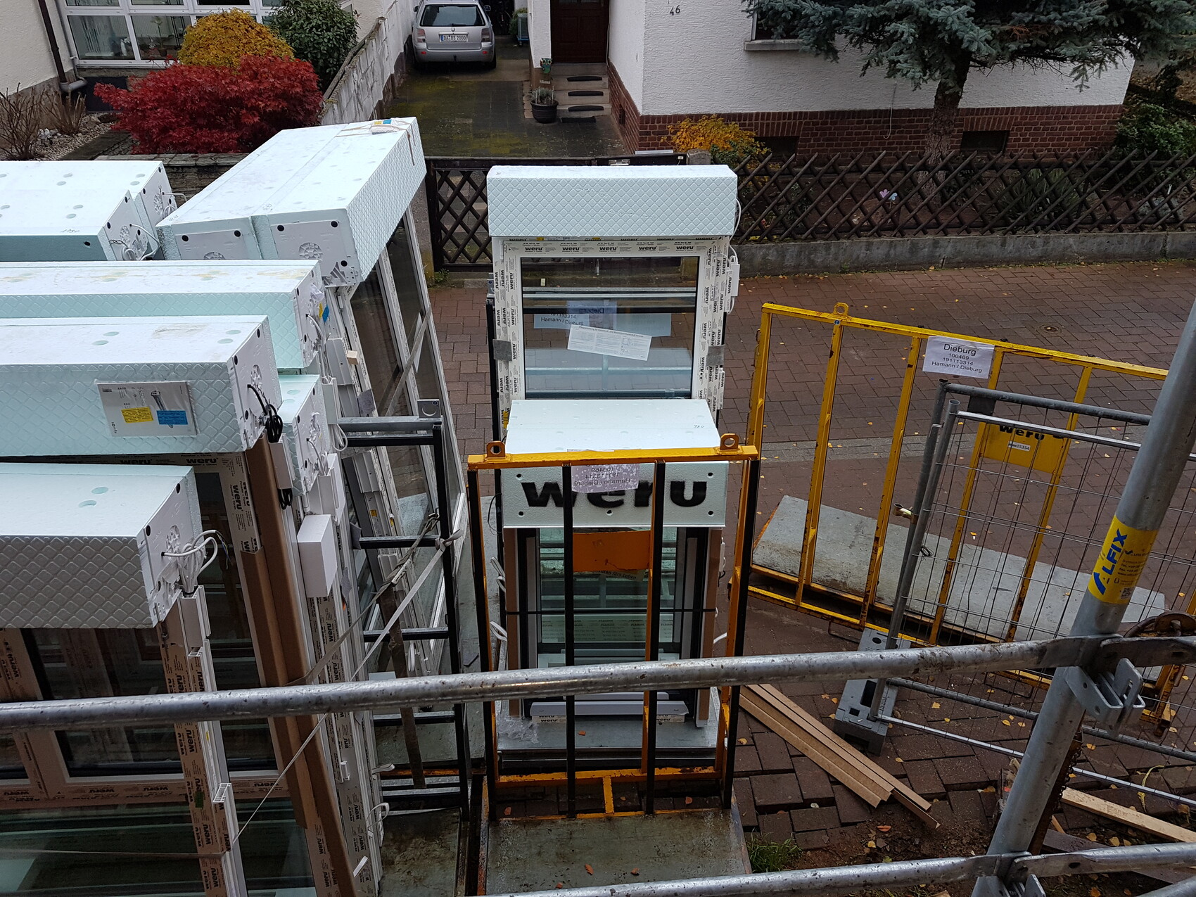 Baustelle mit installierten Fensterrahmen vor Wohnhaus und Baugerüst
