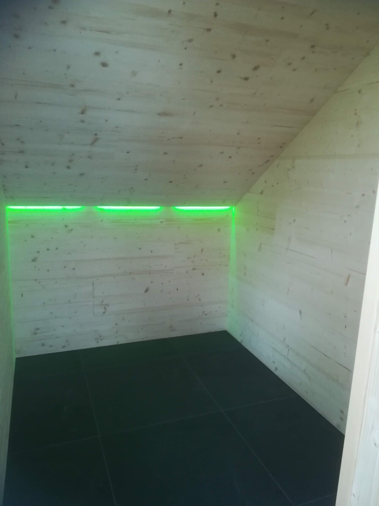 Small room with light wood walls and green LED light strip along the upper wall edge.