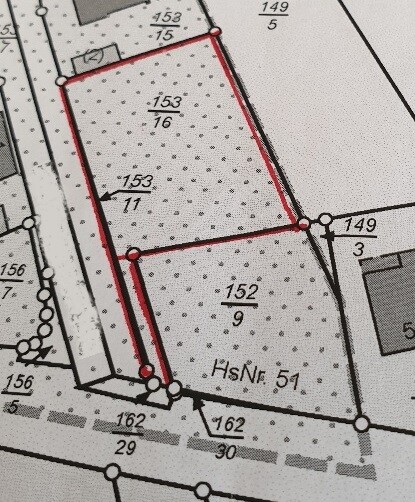 Bauparzelle im Katasterplan mit roter Grundstücksgrenze und umliegenden Straßen.