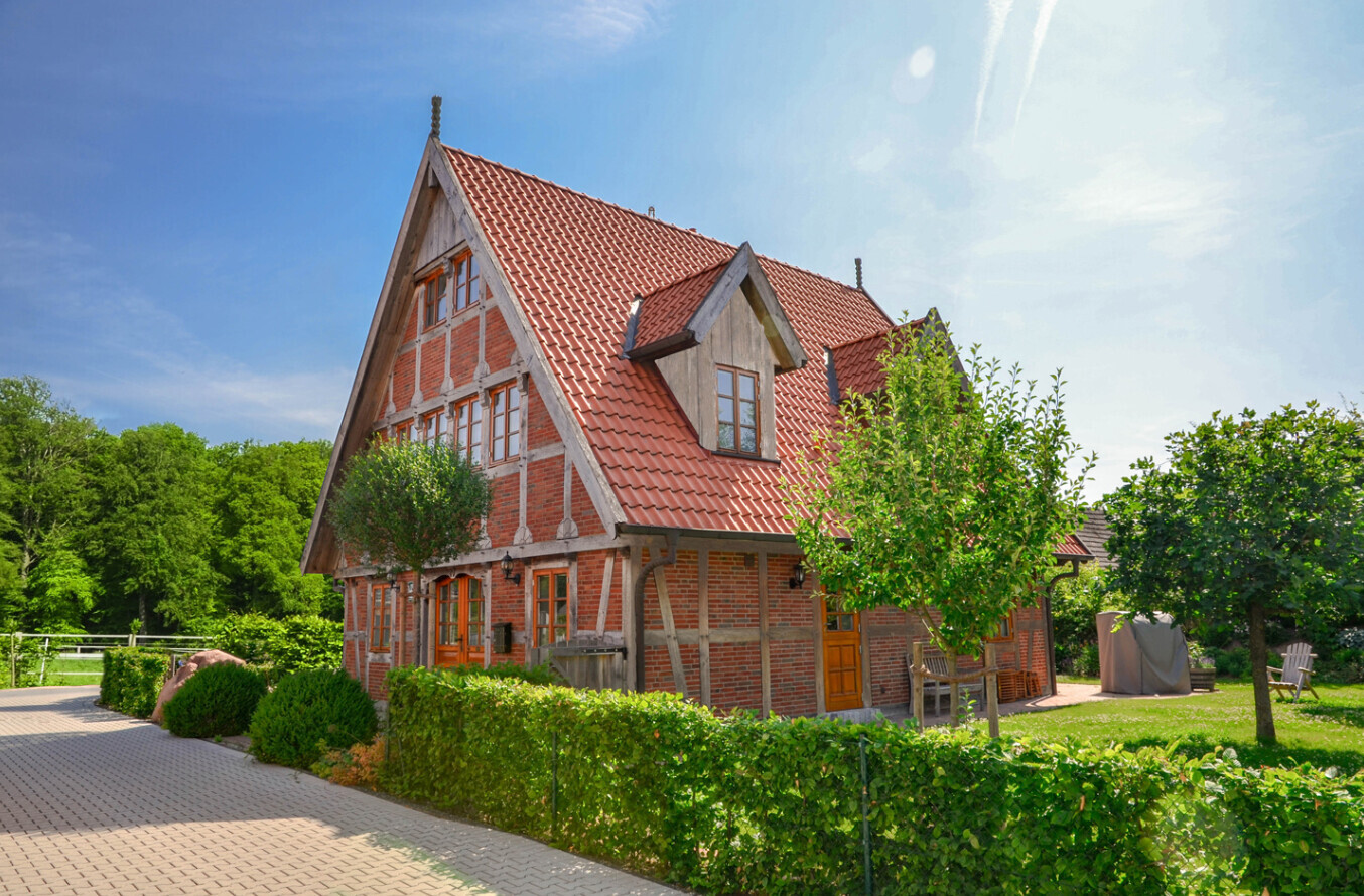 Traditional timber-framed house with red tiled roof, garden and trees.