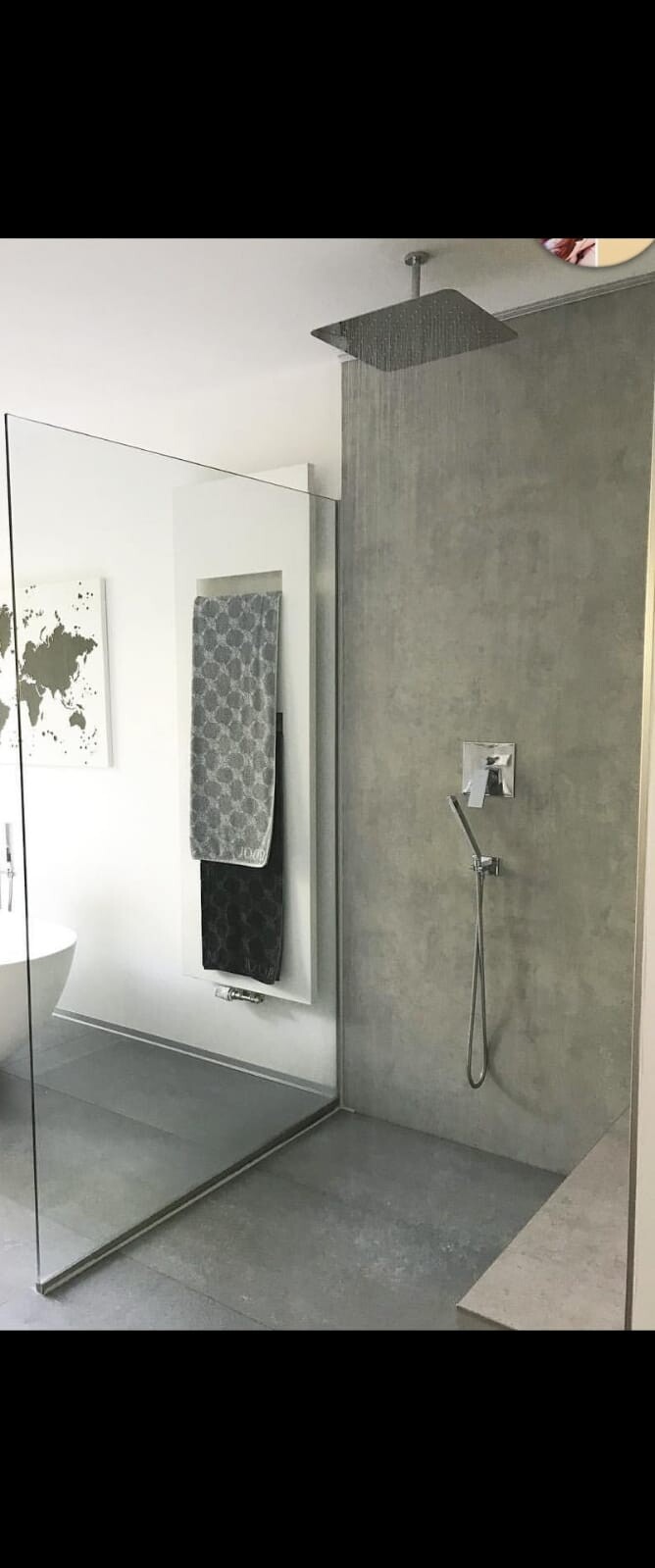Large modern bathroom with walk-in shower, gray concrete wall, and glass partition