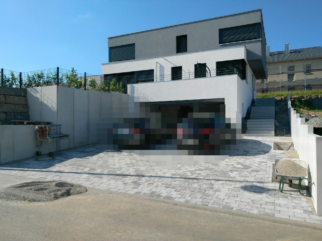 Modern villa with courtyard; two heavily pixelated cars in front of the garage.