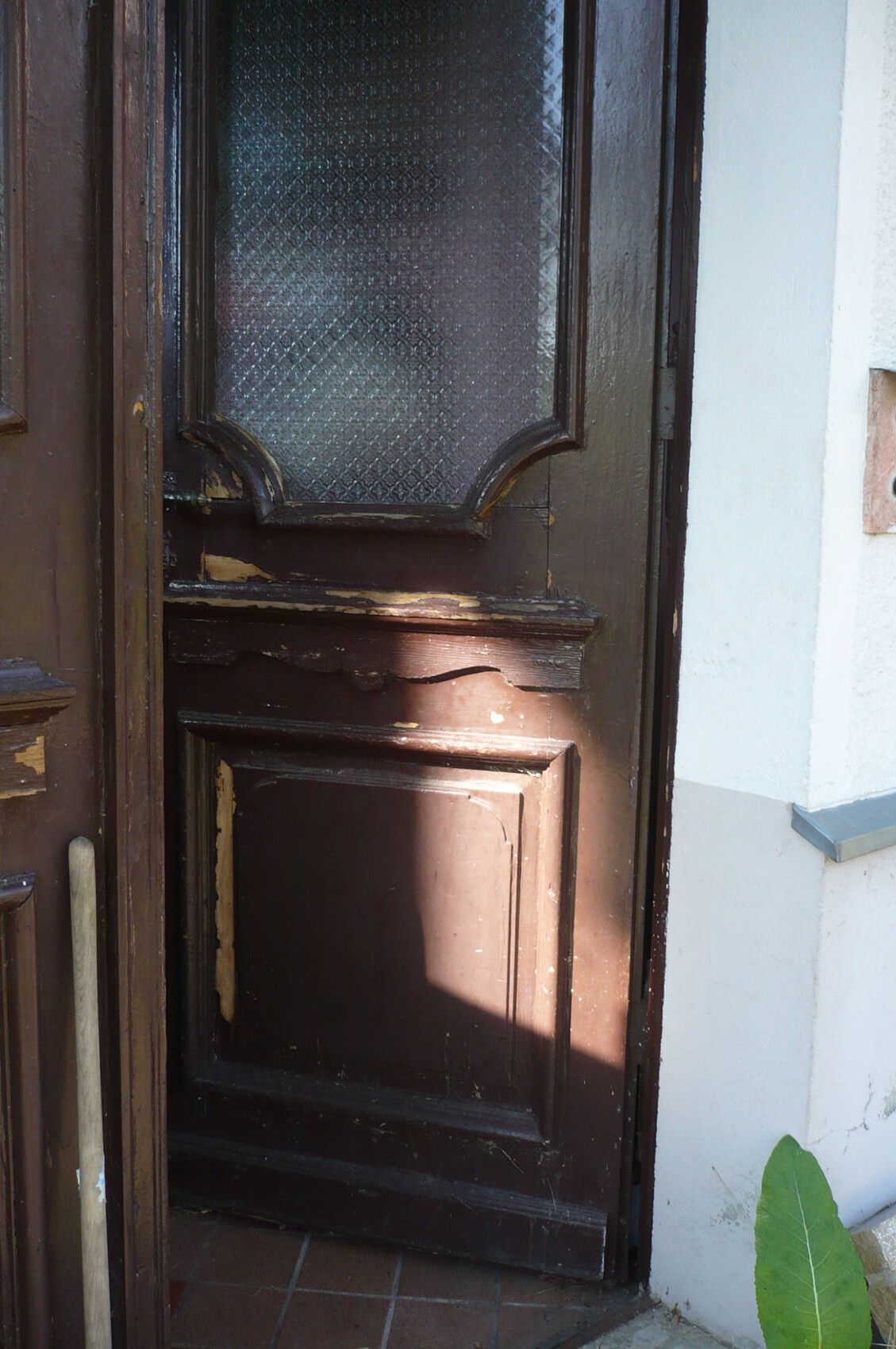 Old brown painted wooden door with decorative glass window in the entrance area