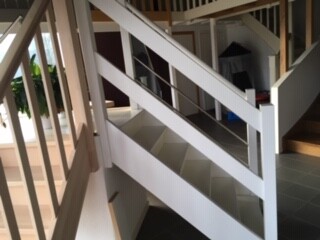 Inside view of a bright white staircase with wooden railing in the living area
