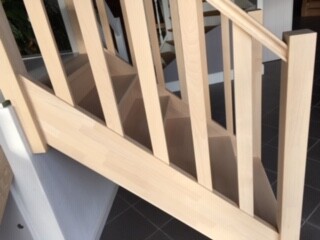 Light wooden staircase railing with vertical balusters on a staircase.