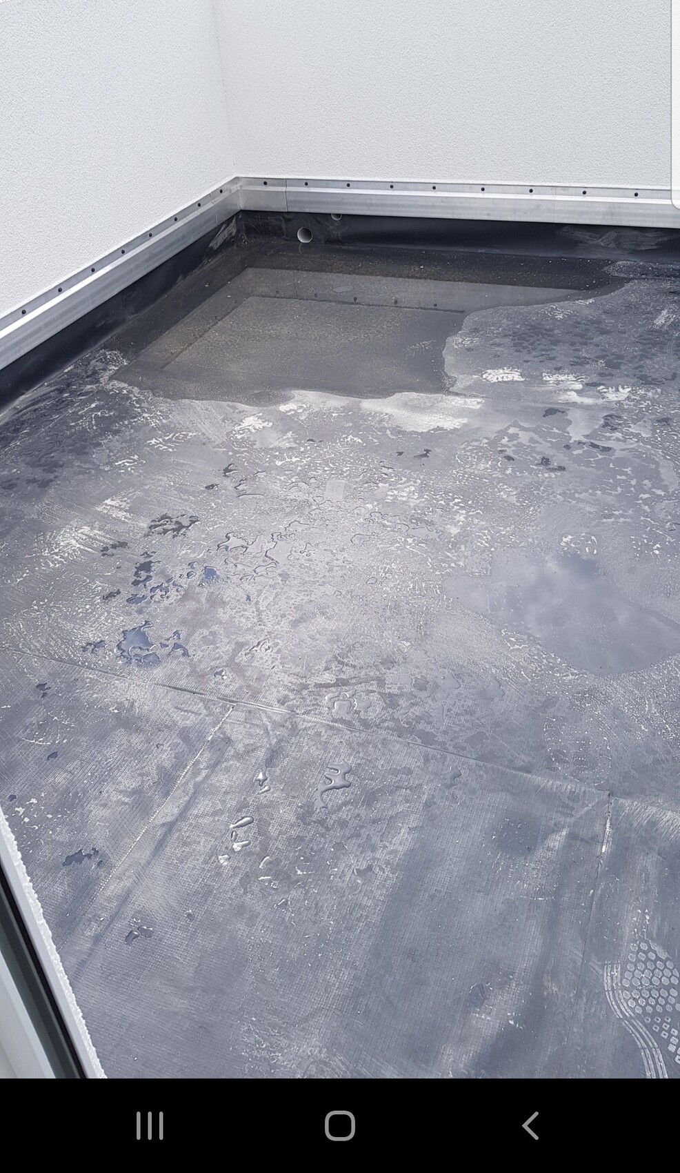 Flat roof/balcony waterproofing: black waterproof membrane, moisture marks and drainage opening in the wall