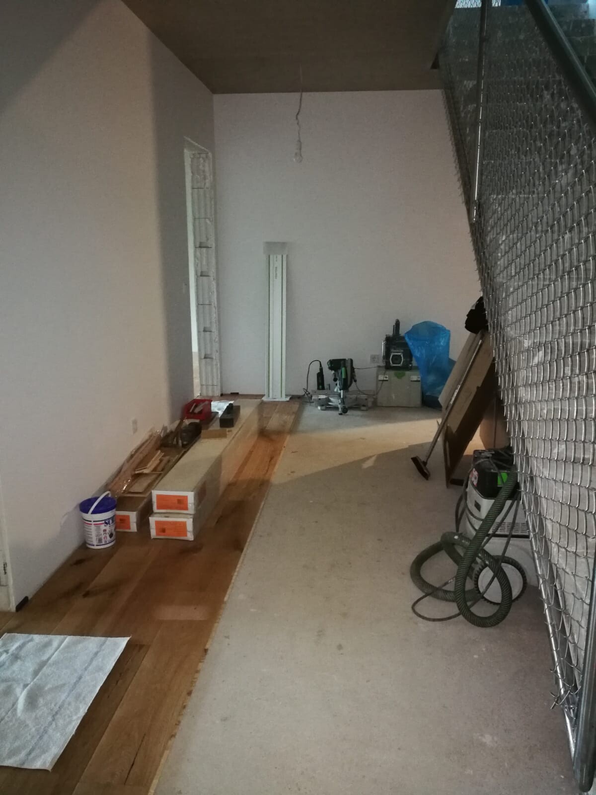 Interior construction site: left wooden planks, crates and tools; right wire mesh wall, background with equipment.
