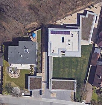Aerial view of a residential house with a green garden, terrace, and forecourt