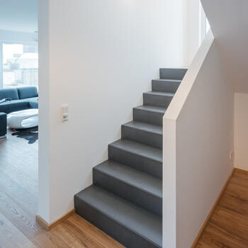 Moderne graue Treppe im hellen Innenbereich neben Wohnraum