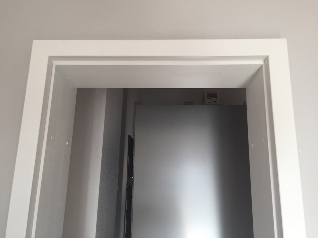 Weißer Türrahmen, Blick in einen Raum mit silberner Metallfront.