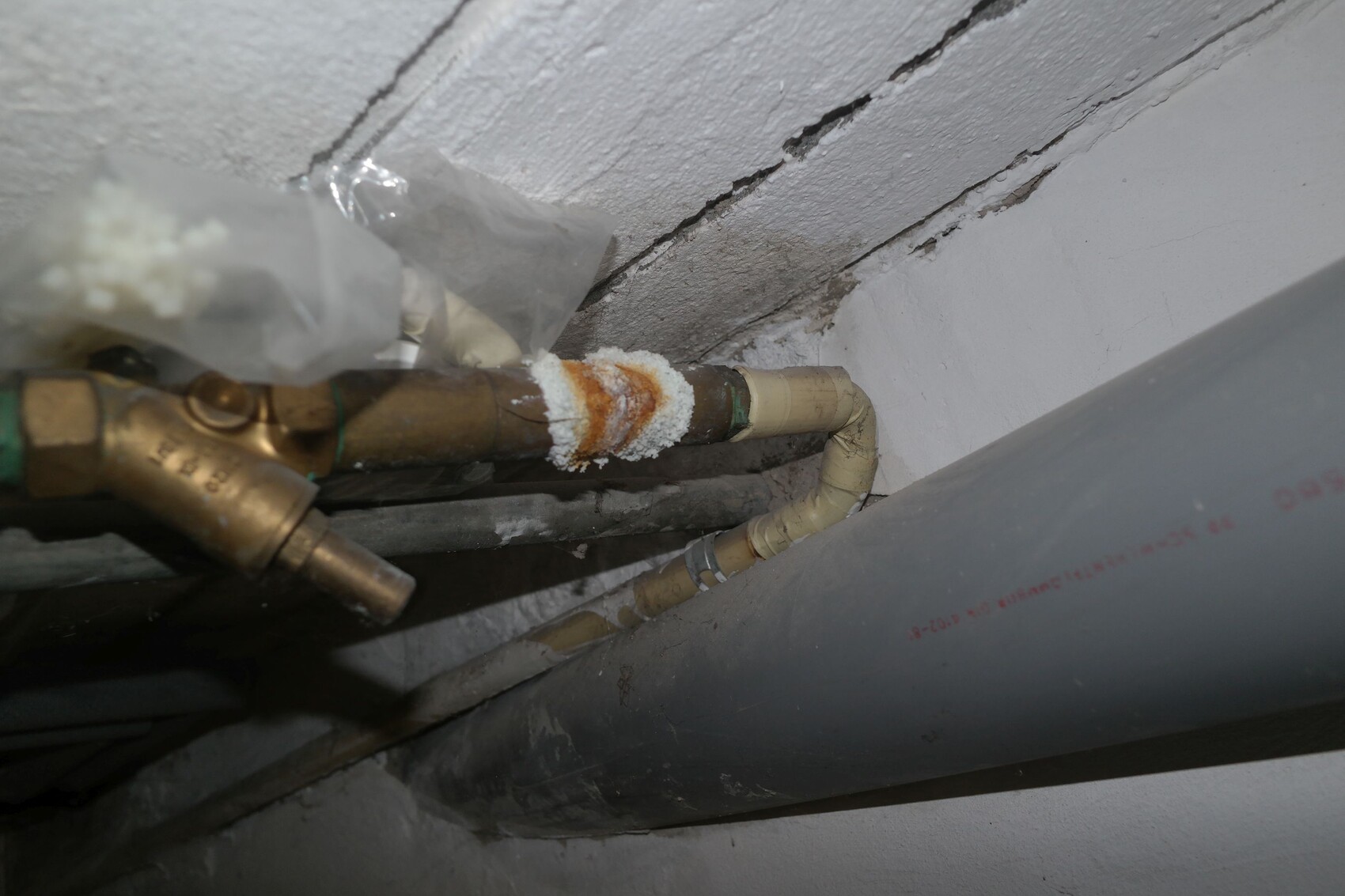 Copper pipe with brass fitting, white crust at the connection; next to it a gray pipe.