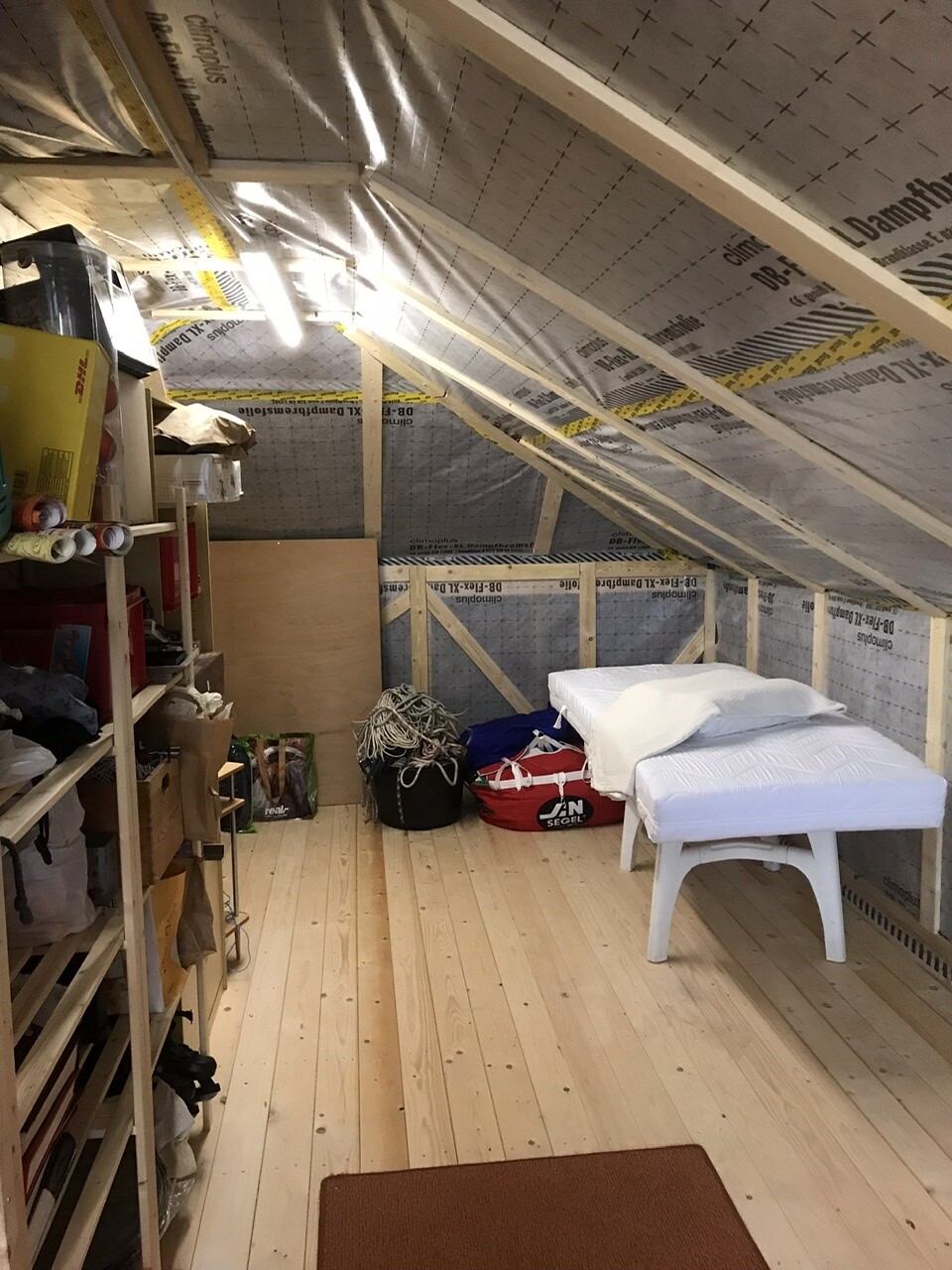 Dachboden/Abstellraum mit Bett, Regalen, Vorräten und Seile.