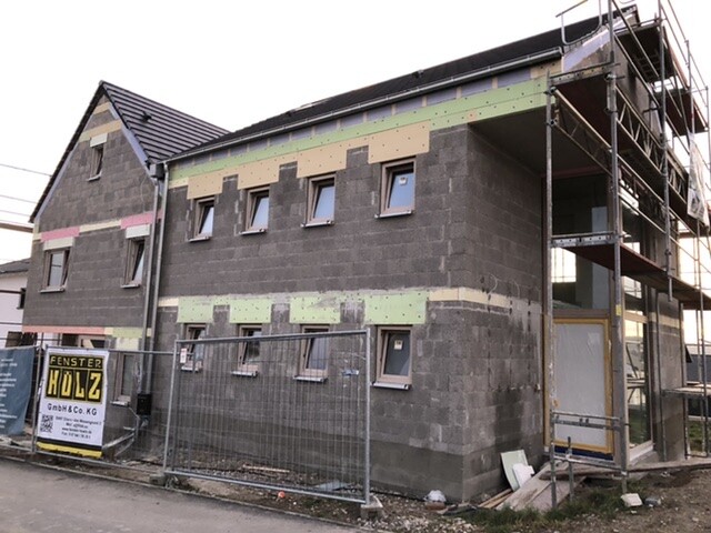 Two-story building under renovation with scaffolding and construction fence in front.