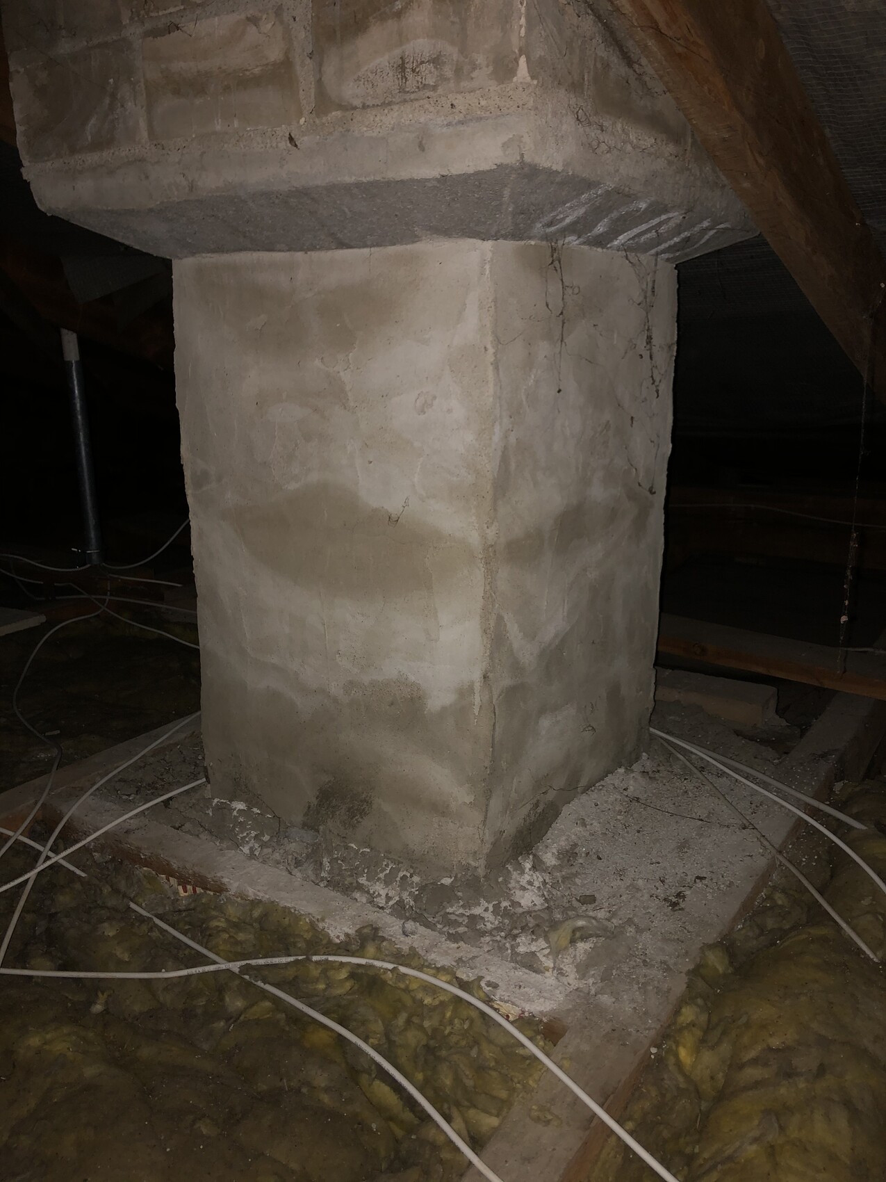 Concrete pillar under wooden beam ceiling; cables and insulation material scattered around the pillar.
