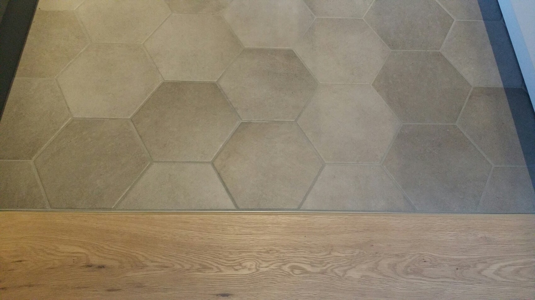 Floor with gray hexagonal tiles, wooden floor edge visible at the bottom.