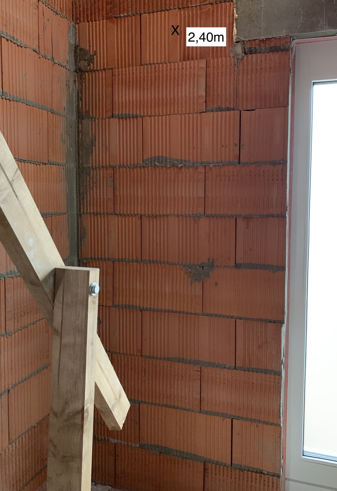 Interior of a construction site: red brick masonry, wooden ladder, and window frame.