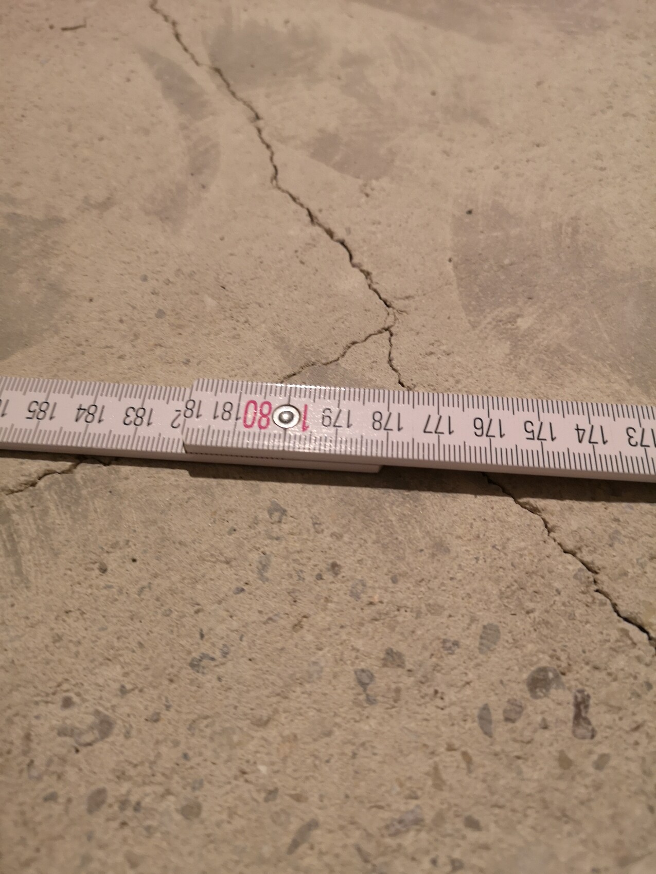 Concrete floor with visible crack and measuring tape.