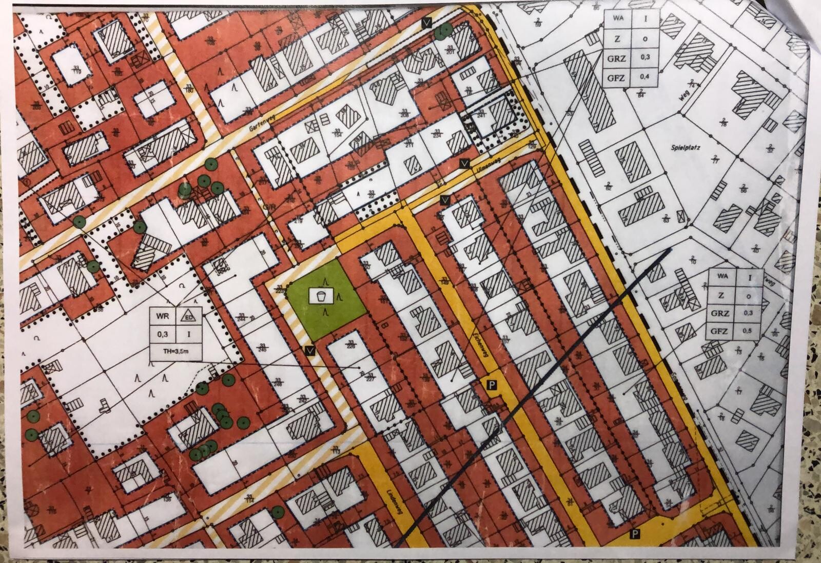 City map with red building zones, yellow streets, green park area and traffic routes.