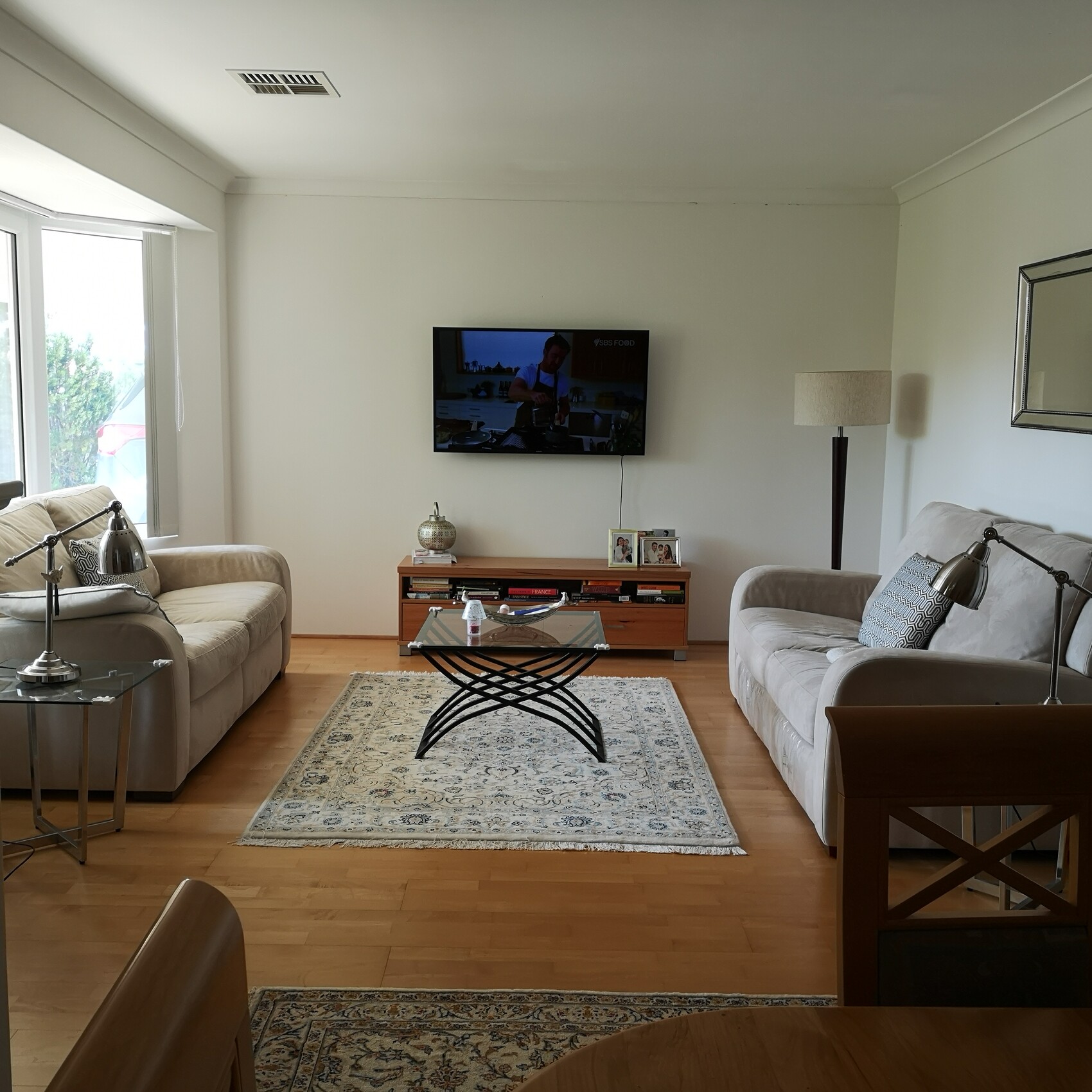 Bright living room with two gray sofas, TV on the wall.