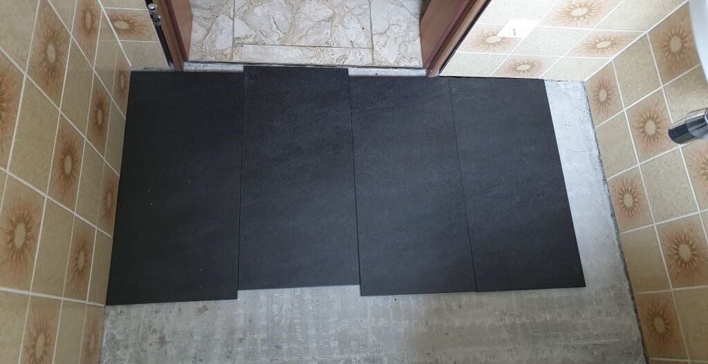 Small bathroom with dark floor tiles and patterned wall tiles