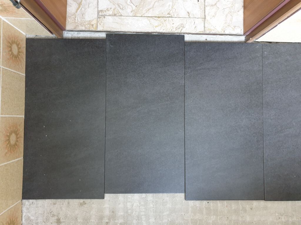 Several dark rectangular tiles neatly placed on the floor in front of a door threshold.
