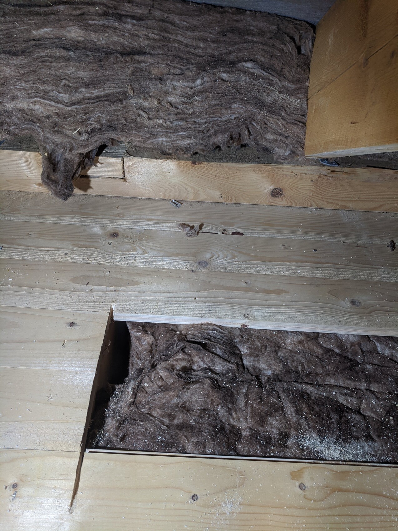 Holzboden mit brauner Dämmwolle; freigelegter Hohlraum im Bodenbereich sichtbar